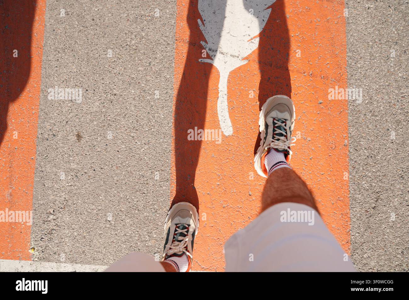 Homme marchant sur une ligne de rue peinte en orange Banque D'Images