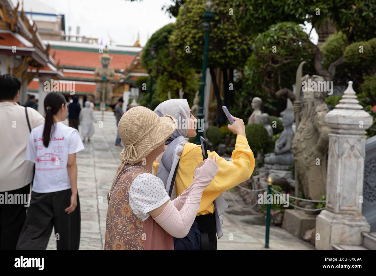 BANGKOK, THAÏLANDE - 7 juin 2026 : Touristes utilisant un smartphone pour prendre une photo, profil latéral Banque D'Images