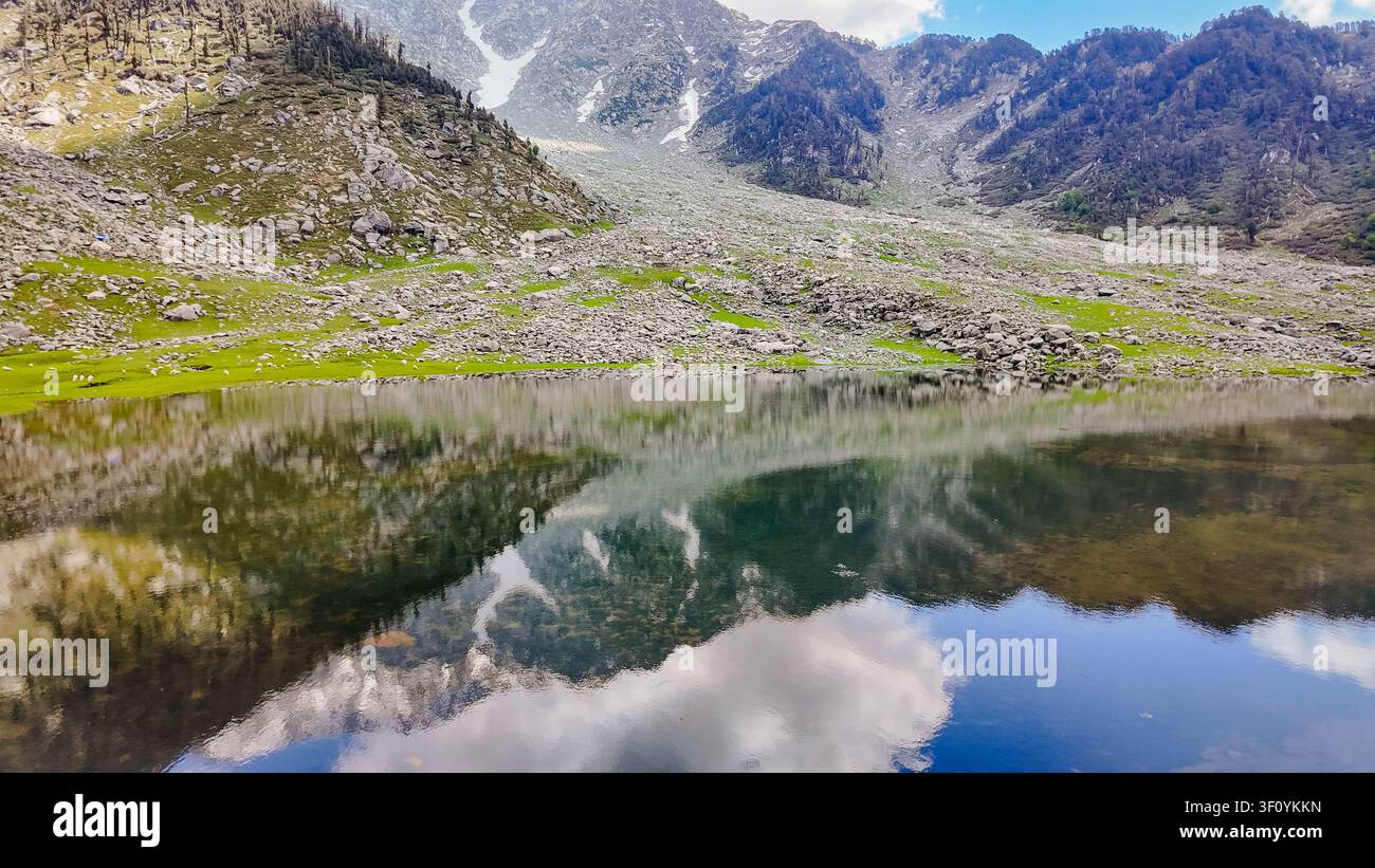 Une vue panoramique à angle élevé du lac Kareri reflétant les montagnes accidentées de l'Himalaya et le ciel bleu au Himachal Pradesh. Banque D'Images