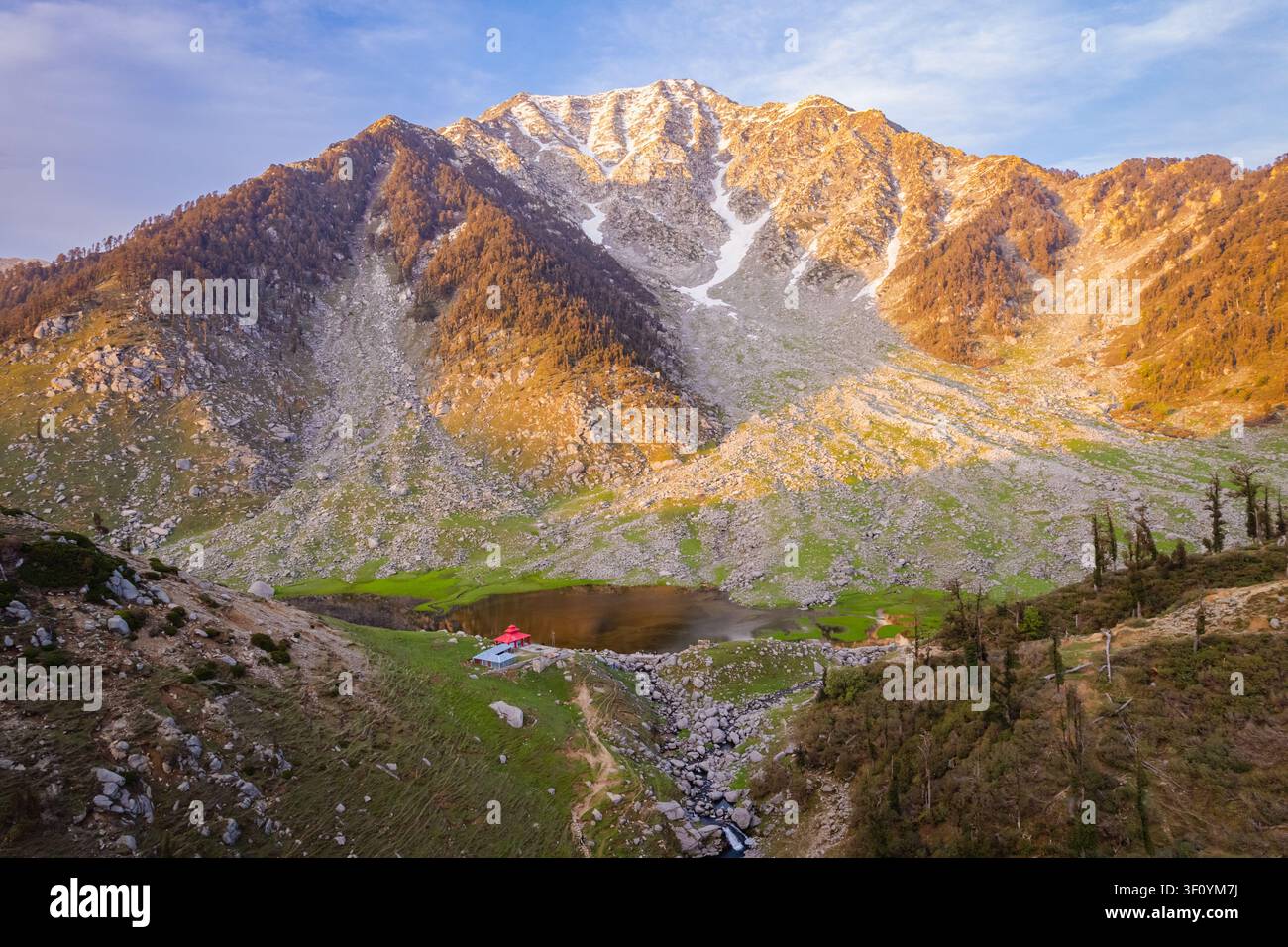 Une vue aérienne du paisible lac Kareri niché sous des sommets montagneux rocheux imposants dans l'Himachal Pradesh, en Inde. Banque D'Images