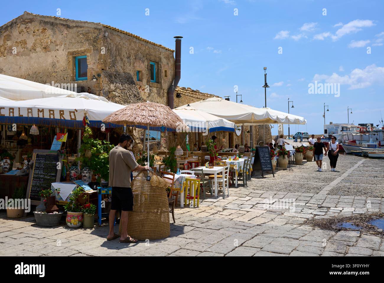 Dîneurs d'été dans une trattoria au bord de l'eau le long du vieux port de pêche à Marzamemi, en Sicile Banque D'Images