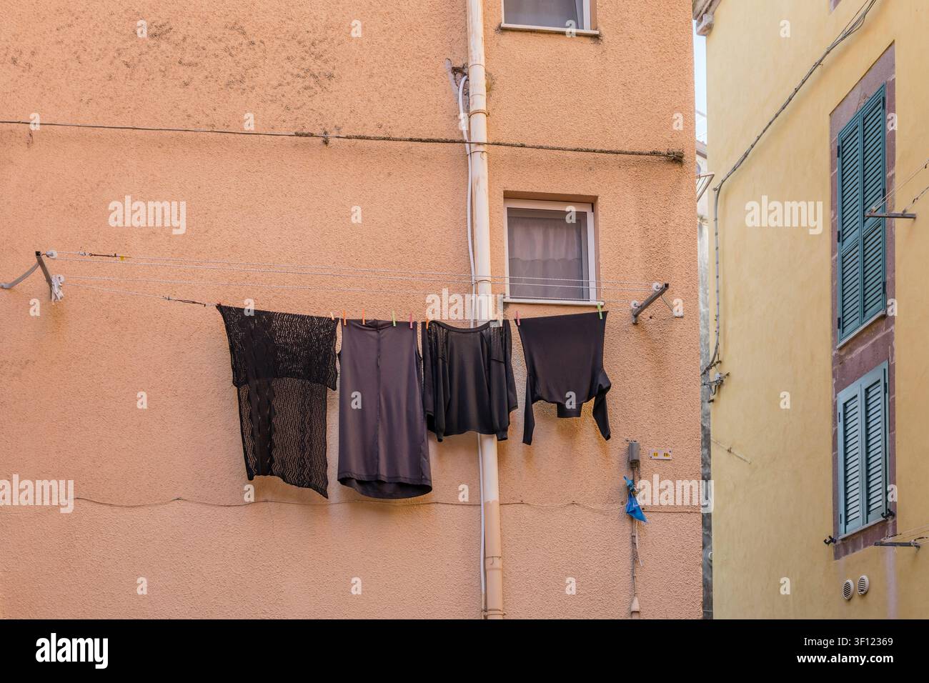Paysage urbain avec du linge noir séchant sur la façade colorée d'un bâtiment haut dans un village historique sur la côte méditerranéenne, pris en lumière vive du printemps à Banque D'Images