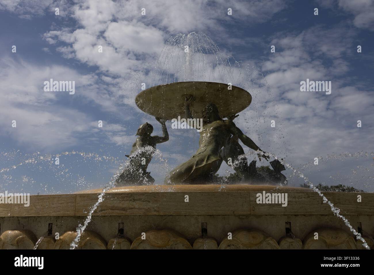 Majestueuse fontaine des Tritons avec de l'eau qui jaillit contre un ciel bleu nuageux à La Valette, Malte. Banque D'Images