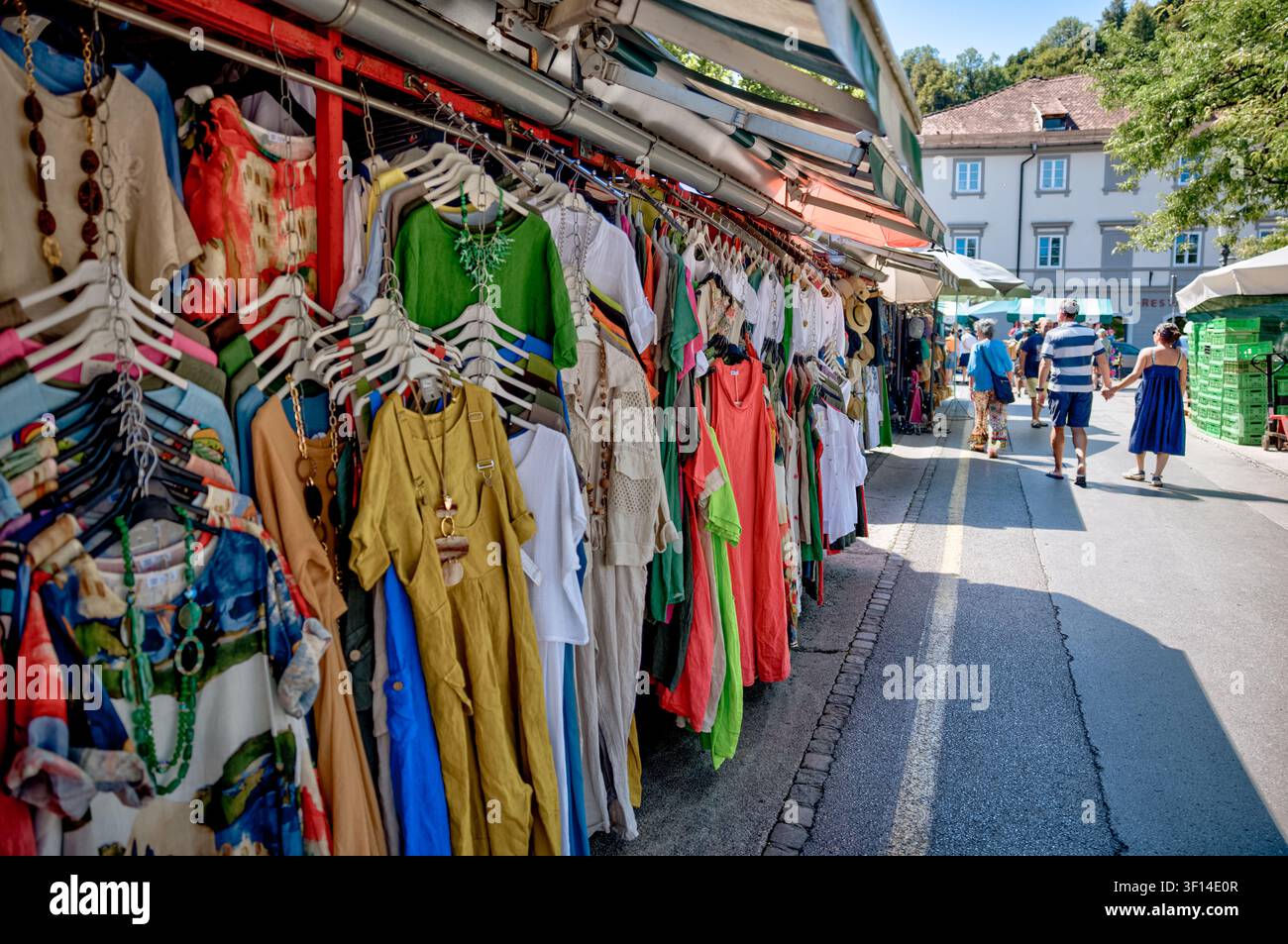 Visiteurs passant devant des étals de vêtements colorés au Marché Central de Ljubljana à Ljubljana, en Slovénie. Banque D'Images