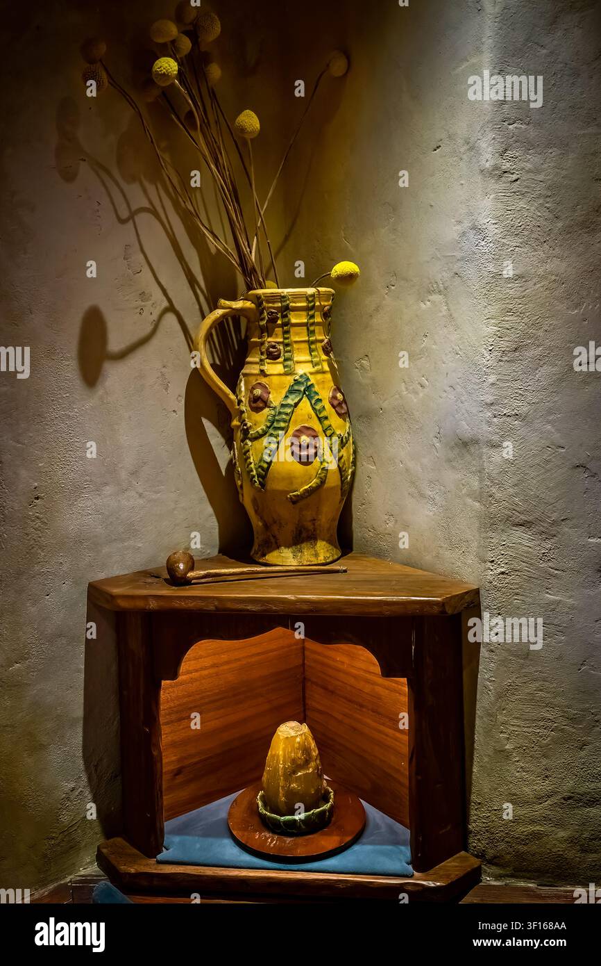 Une vitrine d'angle rustique à l'intérieur d'un terrier de Hobbit au Hobbiton Movie Set à Matamata, en Nouvelle-Zélande, présentant un pichet en céramique jaune décoratif. Banque D'Images