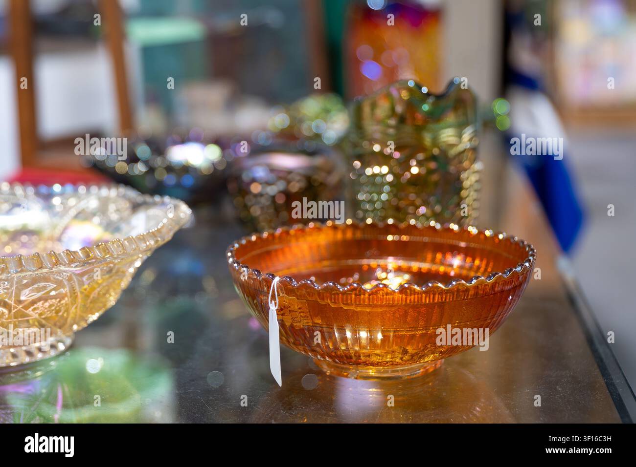 Collection de bols en verre de carnaval vintage dans un magasin d'antiquités, comprenant des pièces en verre pressé irisé ambre soucis et améthyste sombre avec décora Banque D'Images