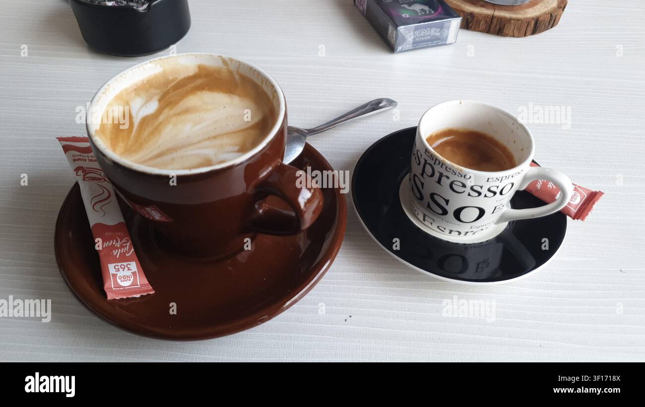 Cappuccino et espresso fraîchement préparés servis côte à côte sur une table de café, mettant en valeur deux classiques du café italien dans un café confortable Banque D'Images