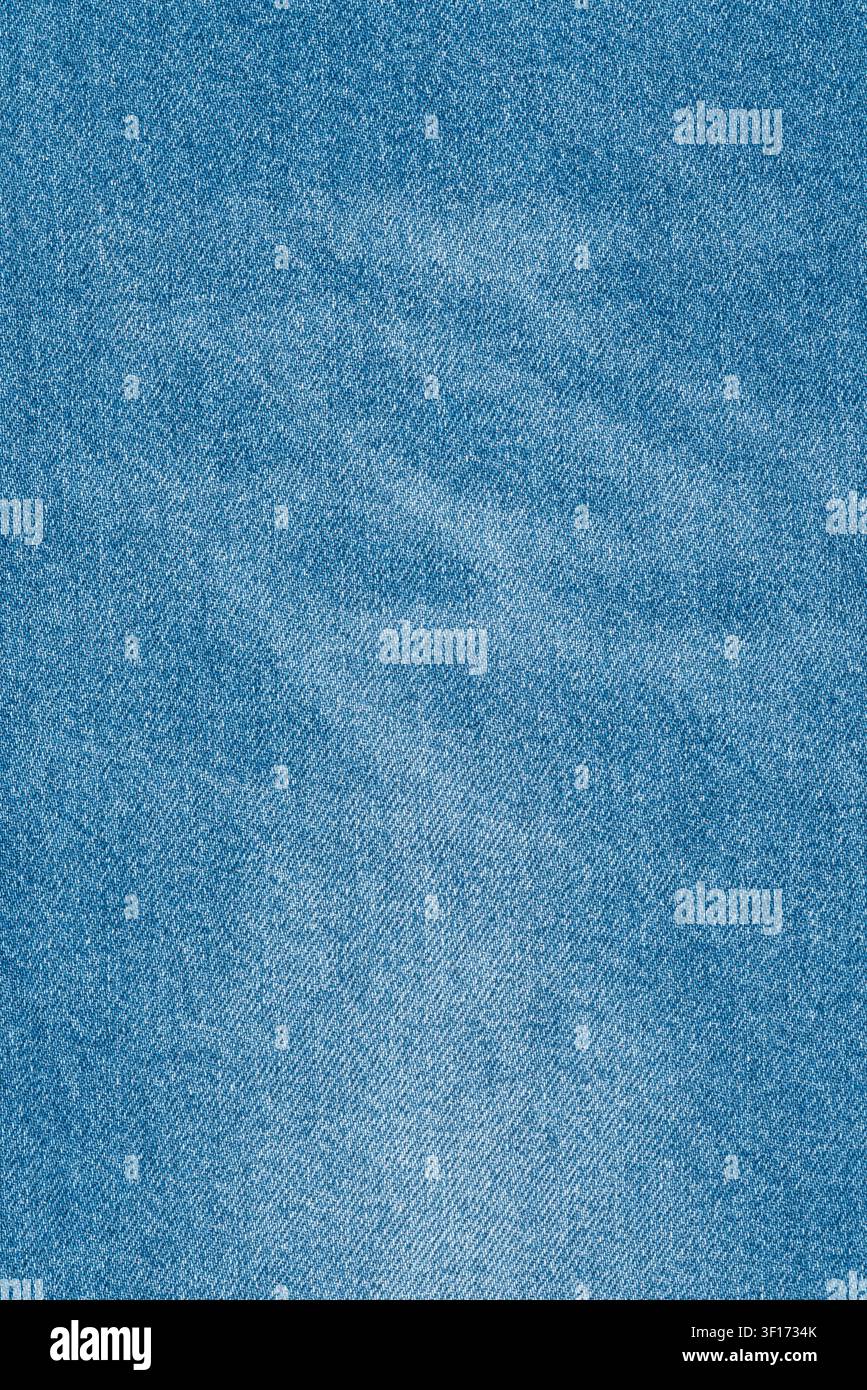 Macro détaillée de la texture denim bleu clair. Fond en tissu jean classique avec trame visible et zones délavées. Polyvalent, décontracté et intemporel Banque D'Images