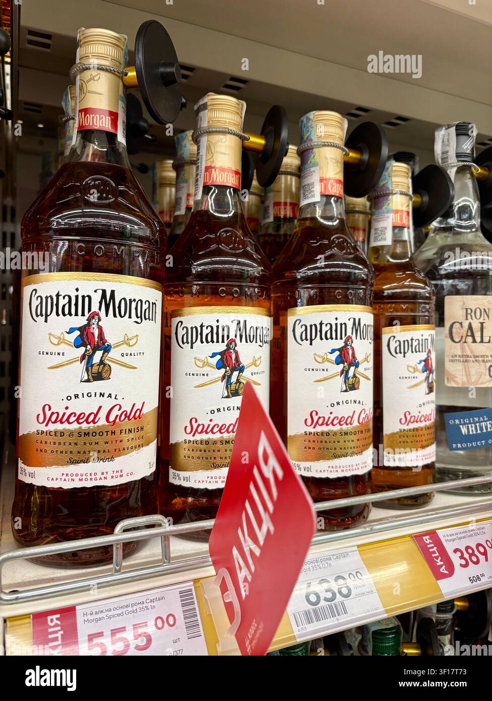 11.07.2026 Ukraine, Kharkov Rangée de bouteilles de rhum Captain Morgan Spiced Gold sur une étagère de supermarché avec étiquettes de prix discount Banque D'Images