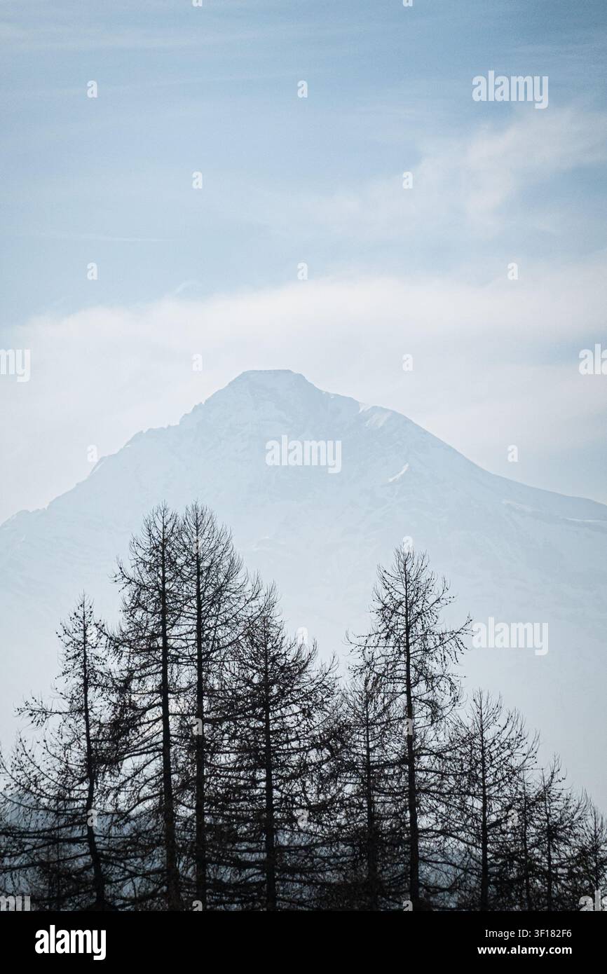 Sommet alpin enneigé émergeant au-dessus des nuages dans la vallée de Suse près de Sauze d'Oulx, Piémont, Italie Banque D'Images