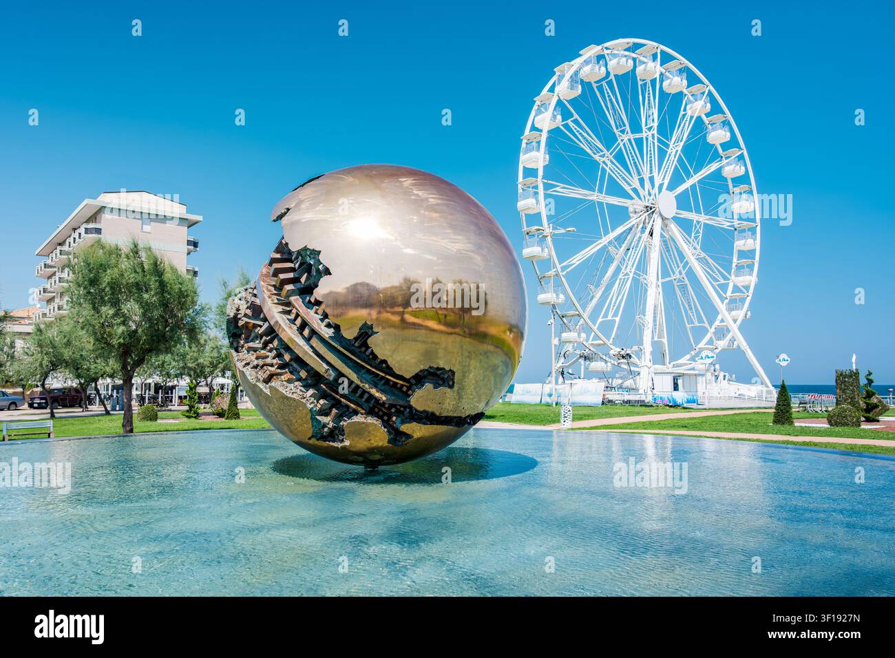 Sculpture sphérique reflétant le paysage urbain avec grande roue à Pesaro Banque D'Images