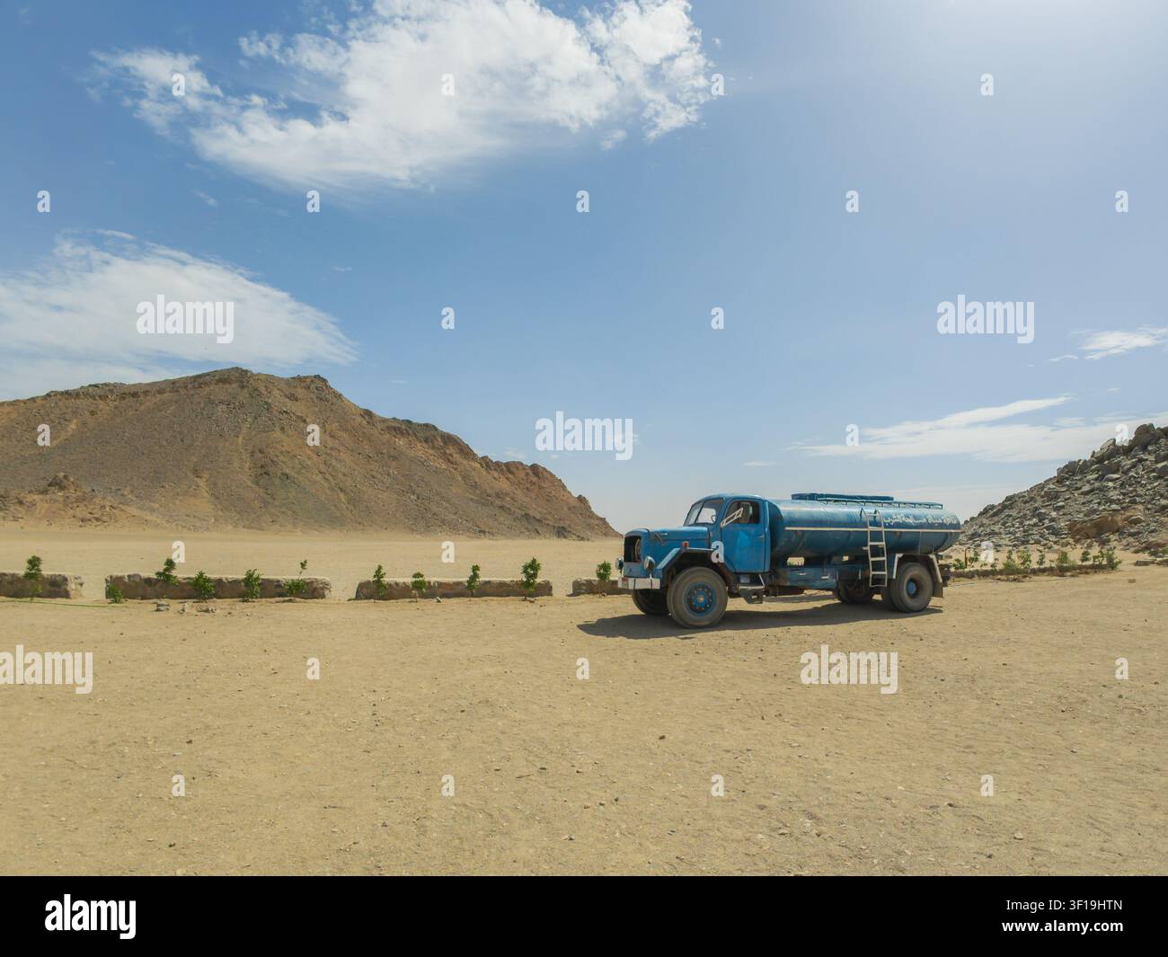 Camion-citerne bleu vintage dans un paysage désertique rocheux sous un ciel bleu Banque D'Images