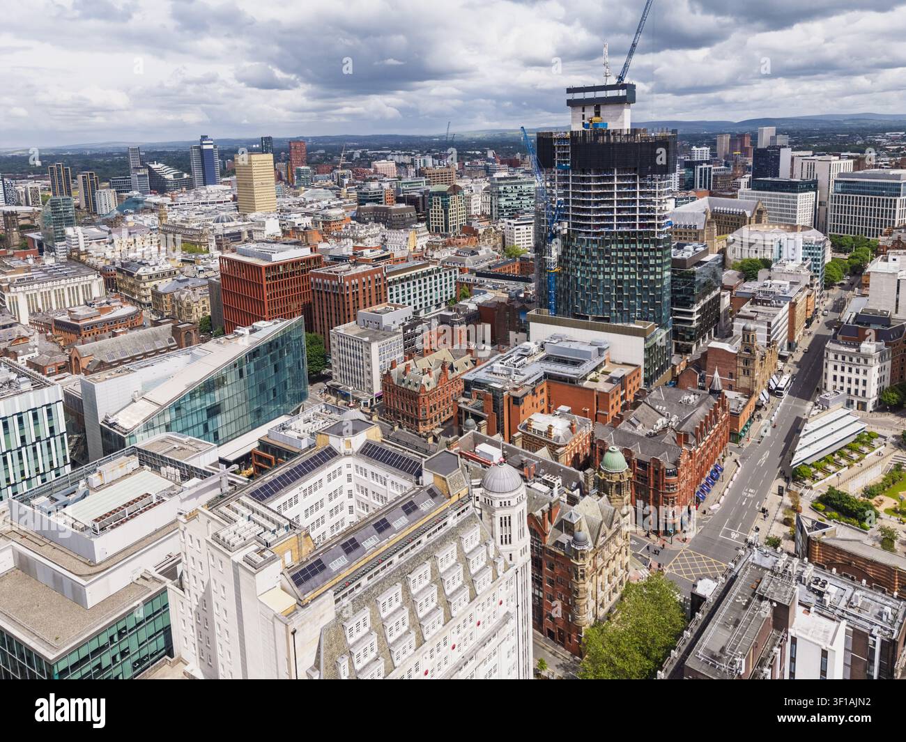 Vue aérienne du centre-ville de Manchester mettant en vedette un gratte-ciel en construction entouré de bâtiments historiques en briques et d'architecture moderne Banque D'Images