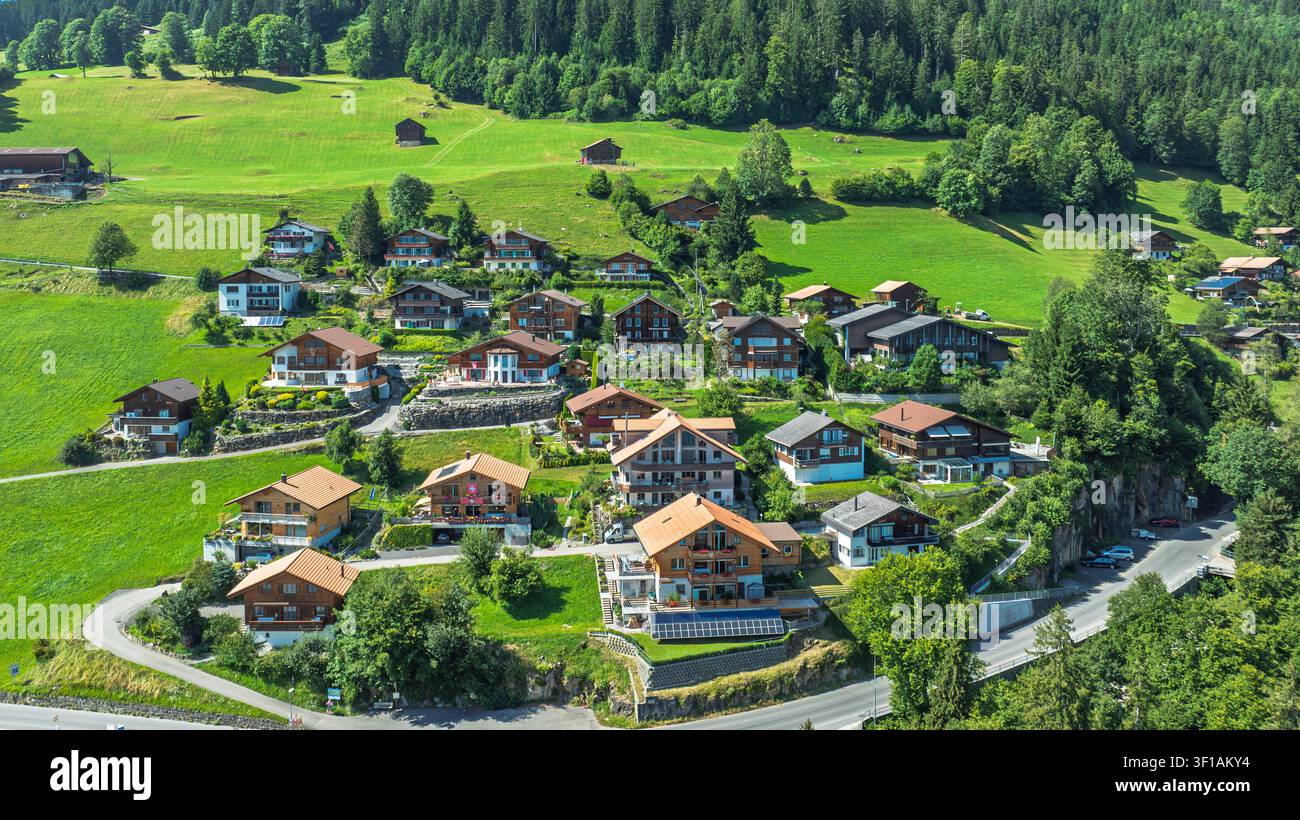 Vue aérienne d'un village suisse pittoresque avec des chalets en bois dans le paysage alpin verdoyant Banque D'Images