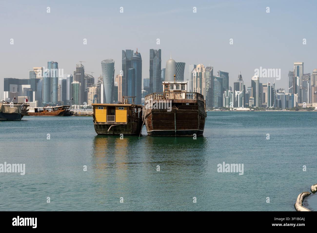 Doha, Qatar - 1er février 2026 : Une vue de l'après-midi de deux bateaux traditionnels en bois dhow amarrés ensemble dans les eaux tranquilles de la corniche de Doha. Banque D'Images