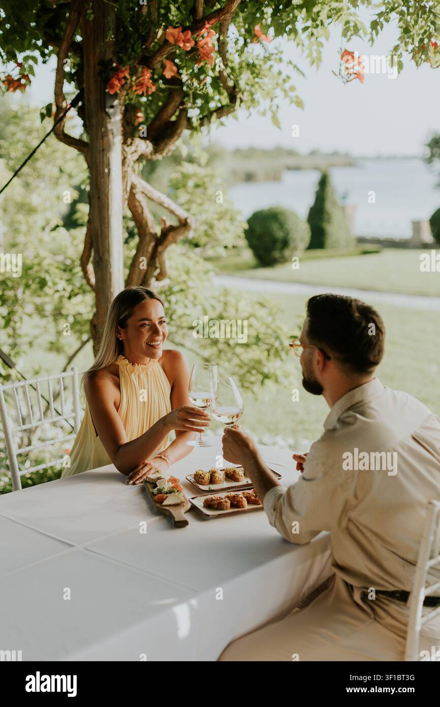 Un couple savoure un délicieux repas ensemble sous une canopée de fleurs. Banque D'Images