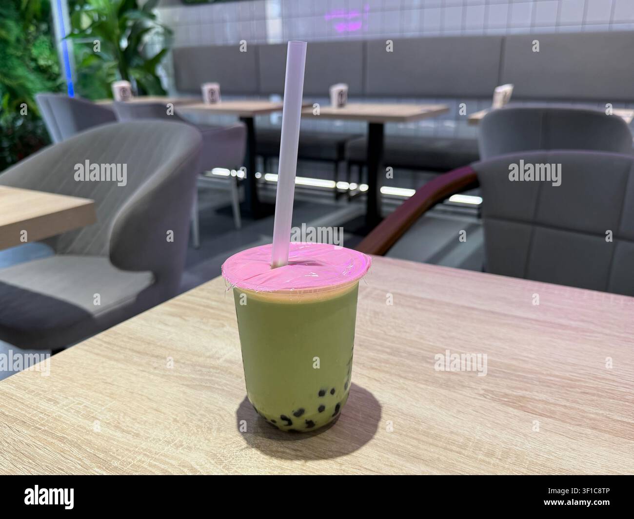 Thé à bulles au matcha avec perles de tapioca servi sur une table de café dans un intérieur moderne avec un flou d'arrière-plan doux. Culture café, tendance alimentaire, style de vie Banque D'Images