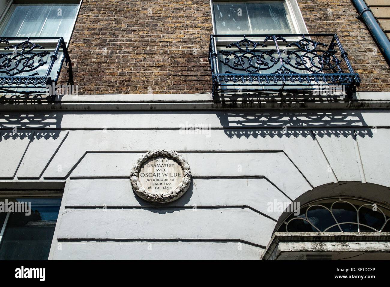 La plaque commémorative de la naissance d'Oscar Wilde sur Westland Row, à Dublin, présentant une couronne circulaire en pierre sur une façade de bâtiment avec des balcons en fer. Banque D'Images