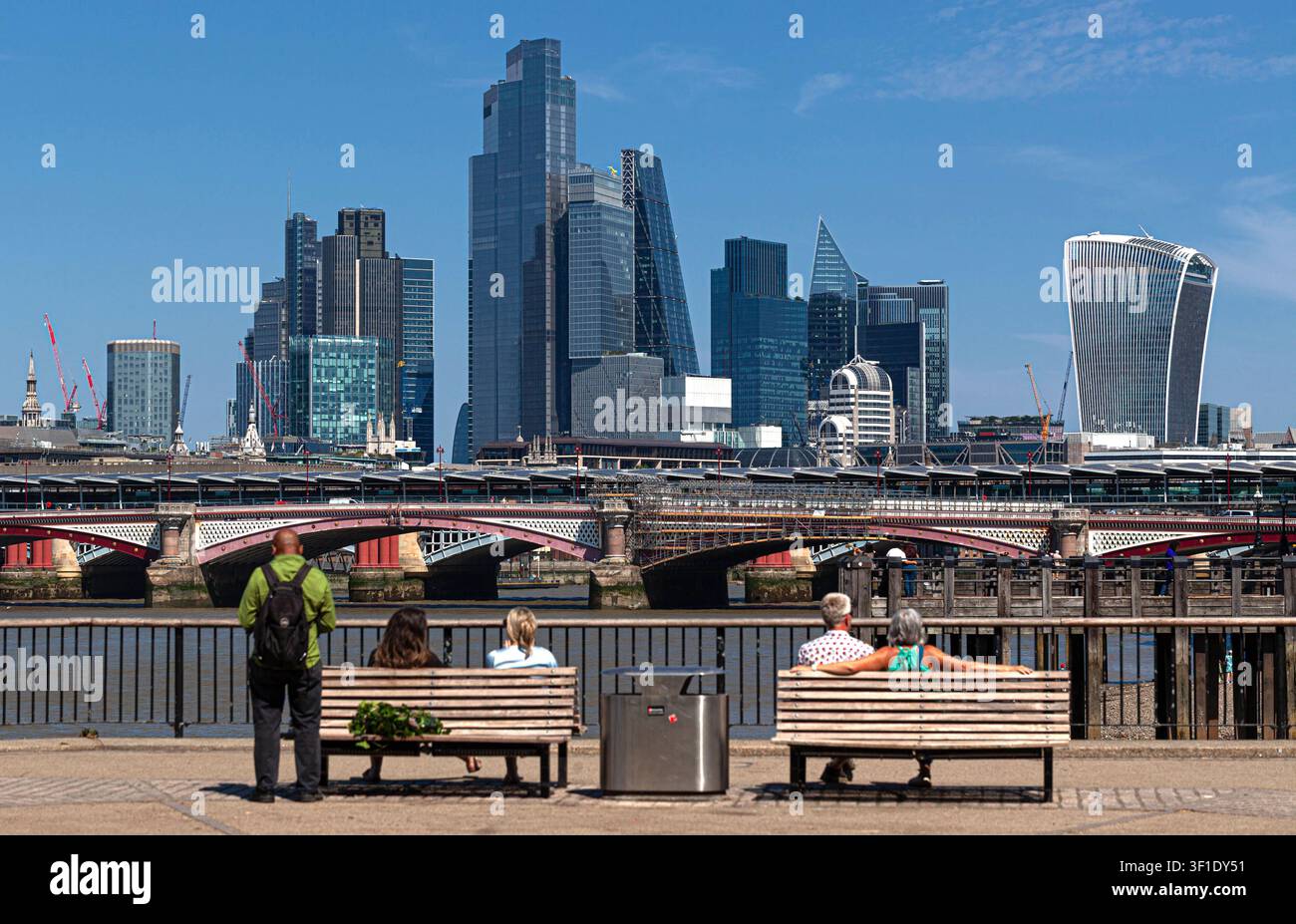 Personnes assises sur des bancs contemplant la skyline de Londres, South Bank Londres, Angleterre, Royaume-Uni. Banque D'Images