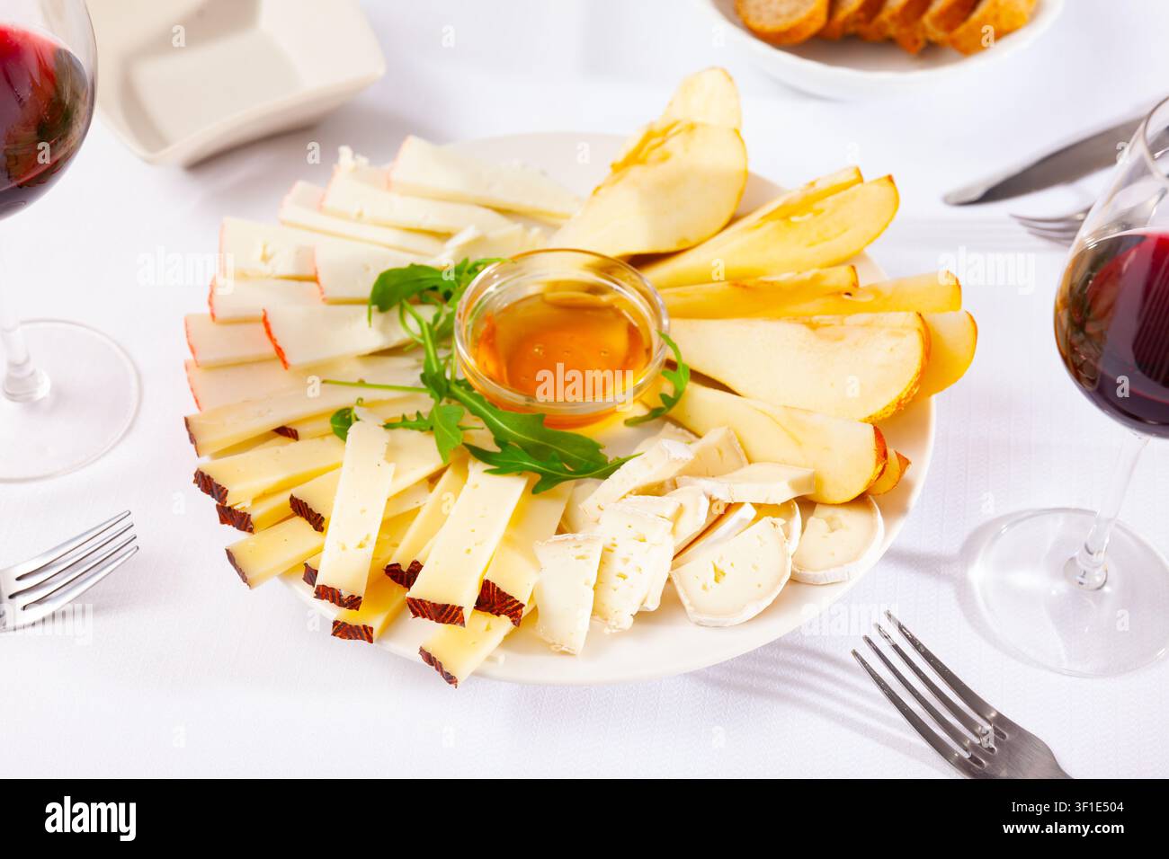 Assiette avec différents types de fromage et une tasse de miel Banque D'Images