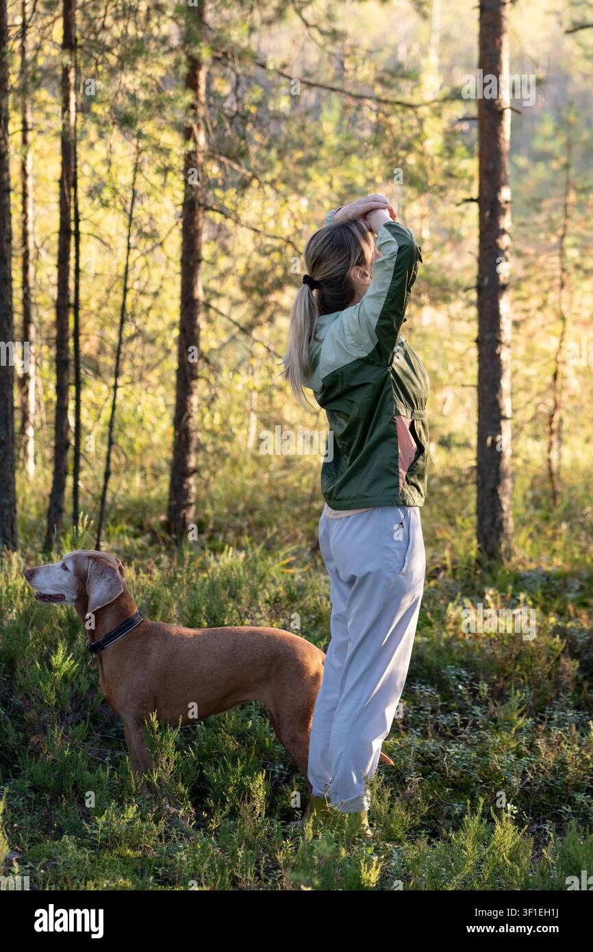 Explorez la nature, une vie saine et le tourisme local, femme accompagnée d'un chien domestique marchant dans la forêt. Banque D'Images