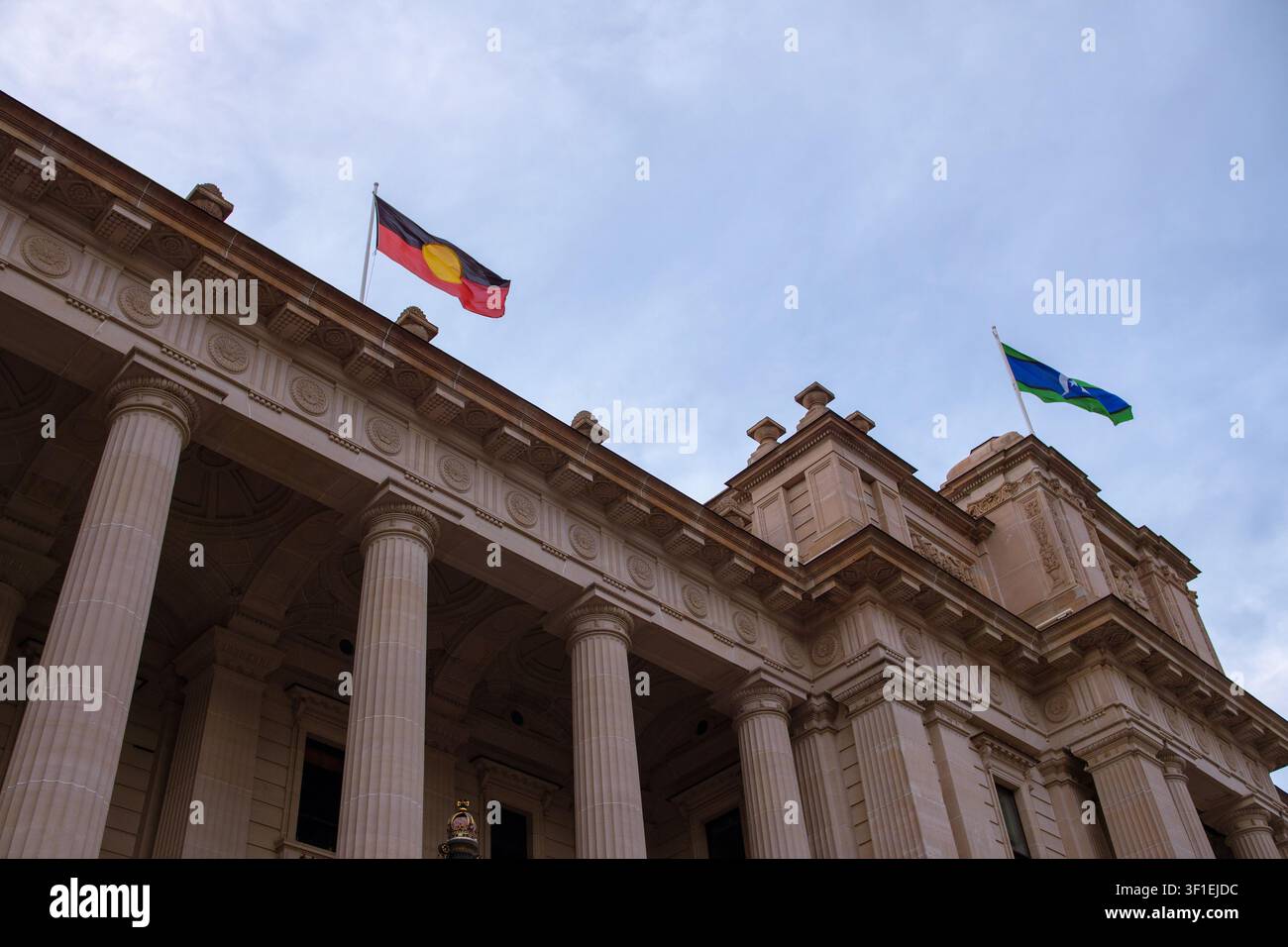 Les drapeaux des Aborigènes australiens et des insulaires du détroit de Torrès flottent au-dessus de l'architecture historique en pierre d'un bâtiment public gouvernemental. Banque D'Images
