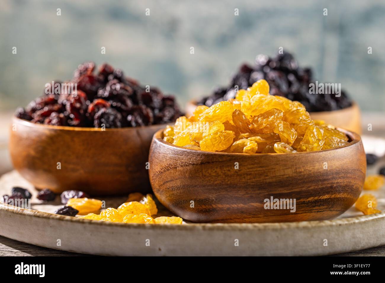 Raisin doré avec un assortiment de raisins secs noirs et rouge foncé dans des bols en bois comme collation saine de fruits secs sur une table rustique Banque D'Images