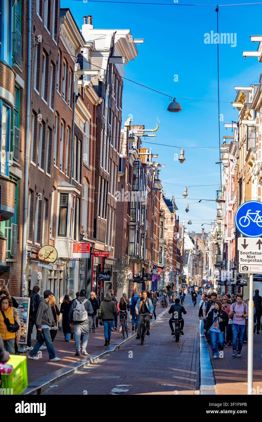 Avec ses maisons étroites historiques penchées à différents angles, cette rue centrale d'Amsterdam est généralement remplie de touristes qui se promènent et de locaux qui font du vélo Banque D'Images
