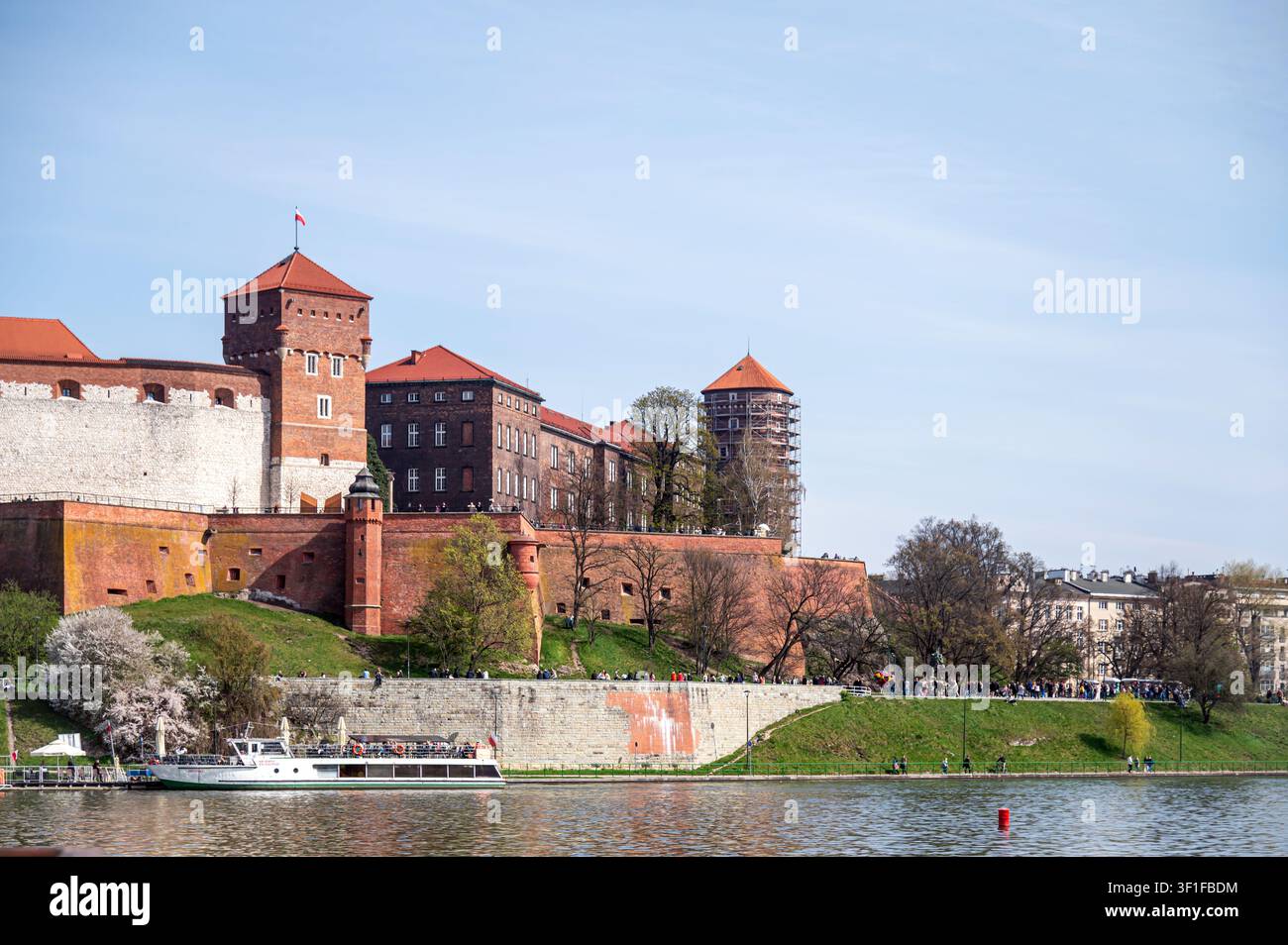 Cracovie, Pologne – 12 avril 2026 : Des gens marchent le long de la rivière tout en explorant le château de Wawel à Cracovie par une journée ensoleillée. Banque D'Images