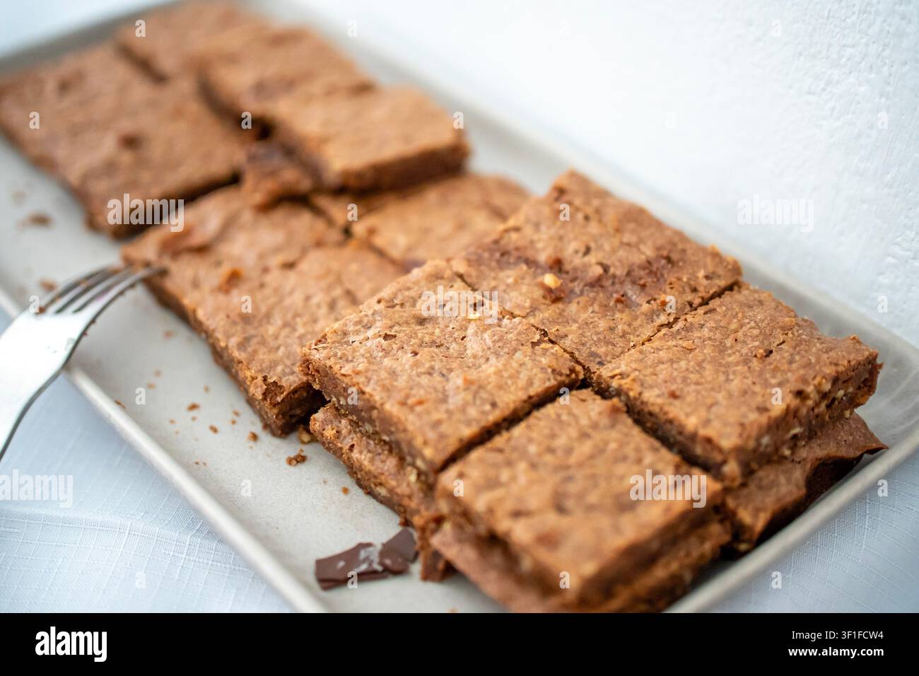 Plateau de gâteau aux noix fait maison coupé en carrés sur une assiette blanche, gros plan du dessert sur le buffet de fête Banque D'Images
