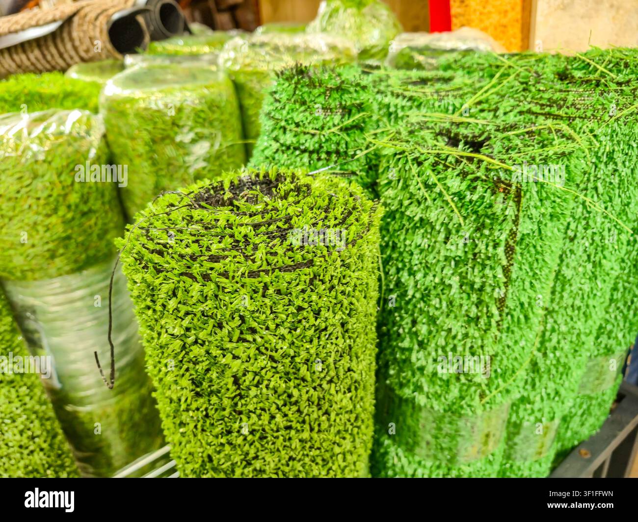 Vue rapprochée d'un gazon artificiel soigneusement roulé, mettant en valeur sa texture verte vibrante et ses fibres denses, parfait pour diverses applications Banque D'Images