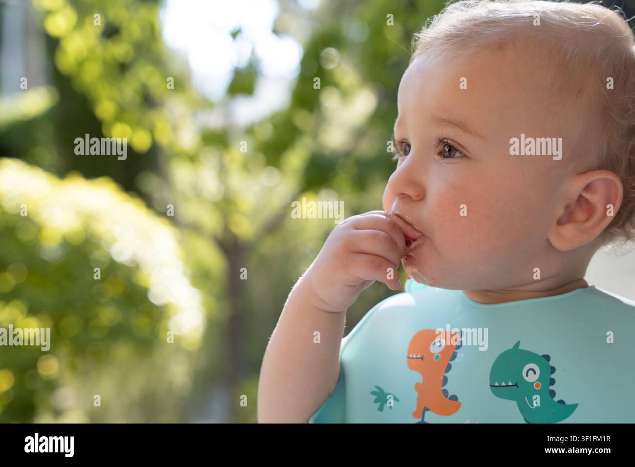 Un bébé heureux démontrant l'indépendance et la coordination lors d'un mode d'alimentation sain. Image de stock commerciale parfaite pour la publicité pour des nutriments biologiques Banque D'Images