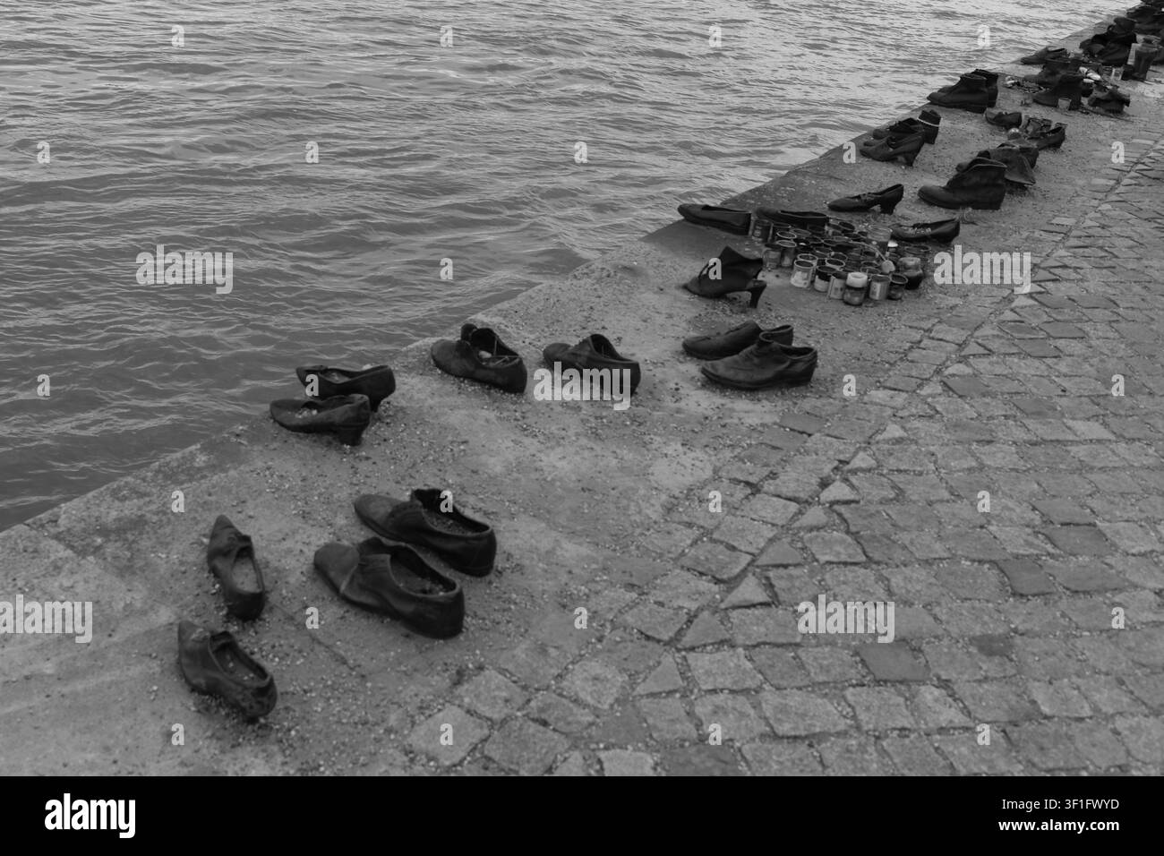Vue monochrome élevée des chaussures en fer le long de la promenade en pierre au mémorial des victimes de l’Holocauste de la Seconde Guerre mondiale « Chaussures sur les rives du Danube » à Budapest Banque D'Images