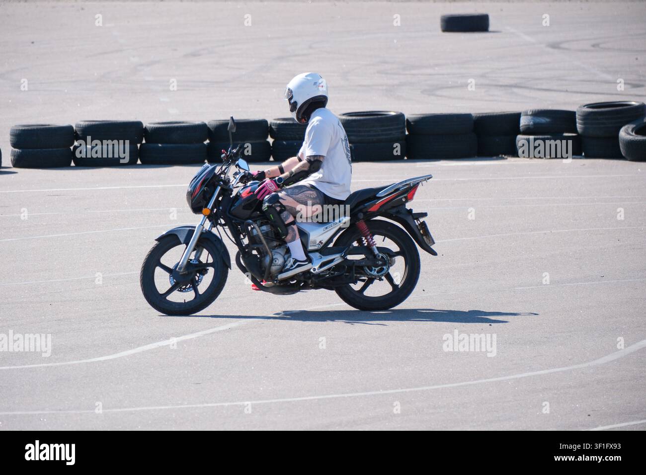 KIEV, UKRAINE, 12 juillet 2026, Un motard portant un casque de protection pratique des manœuvres à basse vitesse sur un terrain d'entraînement à la moto avec buste de sécurité Banque D'Images