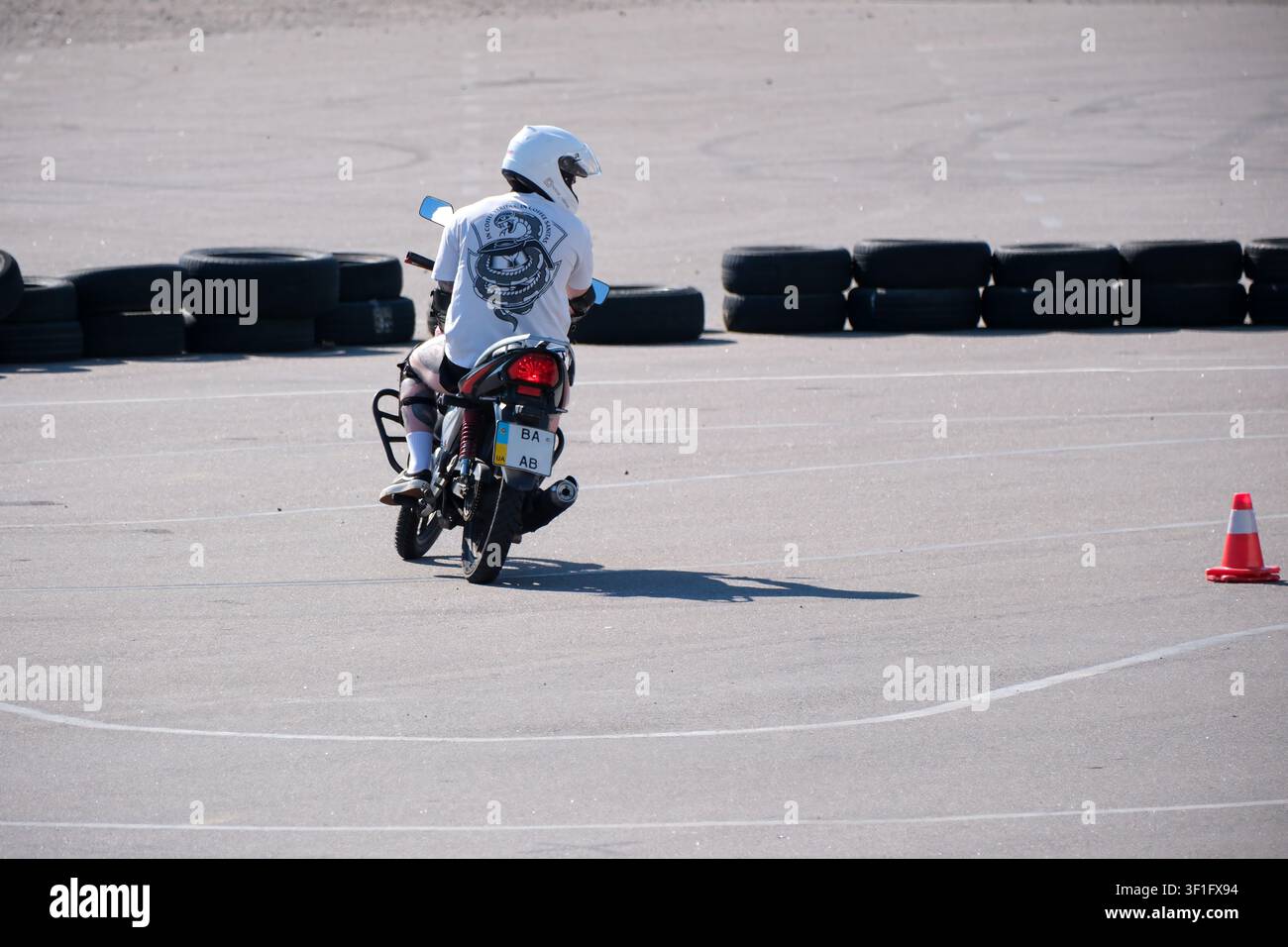 KIEV, UKRAINE, 12 juillet 2026, Un motocycliste portant un casque pratique ses compétences de conduite sur un circuit d'entraînement à la moto marqué par des cônes de signalisation routière Banque D'Images