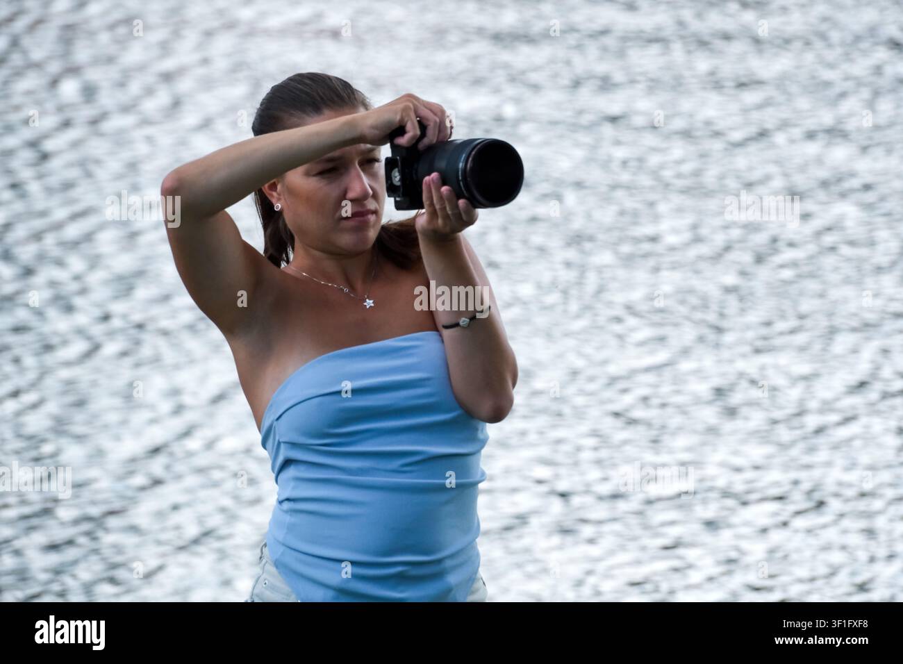 KIEV, UKRAINE, 12 juillet 2026, Une photographe utilise un appareil photo sans miroir avec un téléobjectif pour photographier des actions de wakeboard lors d'un été Banque D'Images
