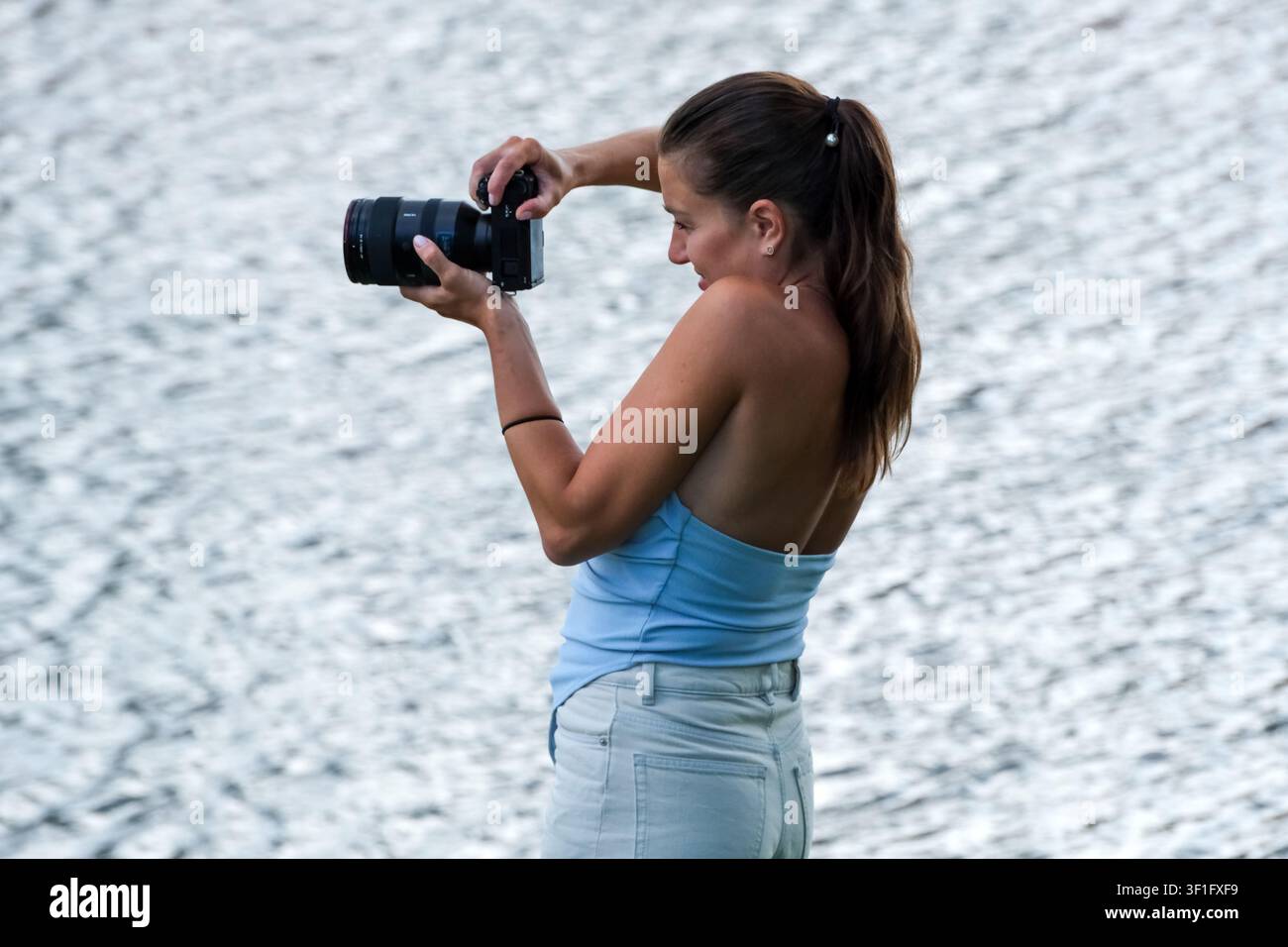KIEV, UKRAINE, 12 juillet 2026, Une photographe utilise un appareil photo sans miroir avec un téléobjectif pour capturer l'action pendant une session de wakeboard sur le Banque D'Images