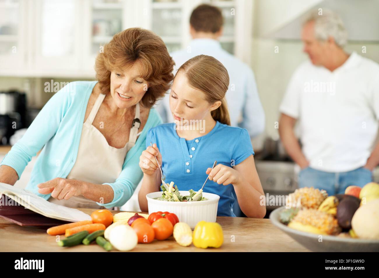 Lecture, recette et grand-mère avec enfant, cuisine et apprentissage des compétences culinaires dans la cuisine ou montrer. Femme âgée heureuse et préparation des repas avec une fille Banque D'Images