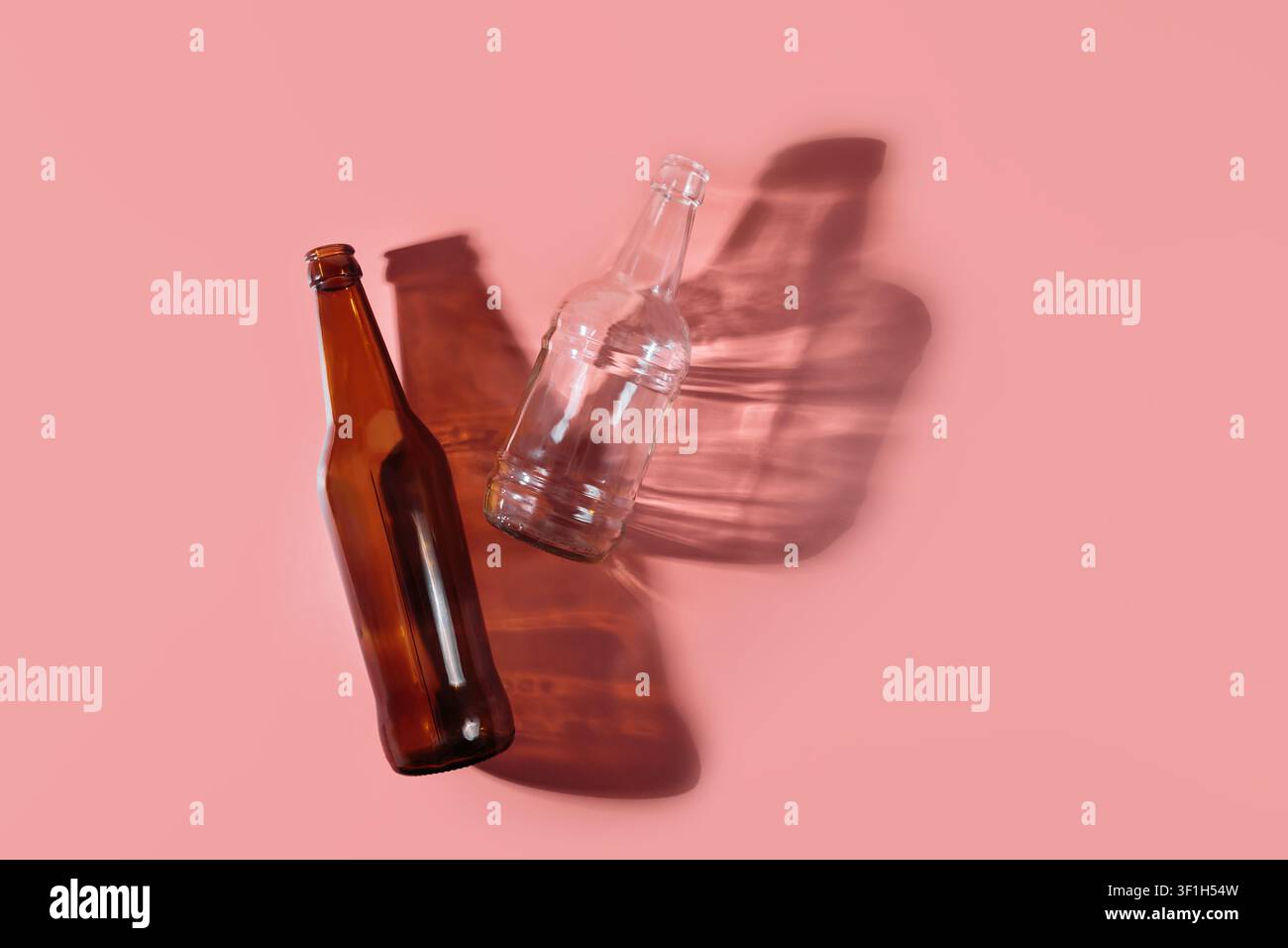 Bouteilles en verre projetant de longues ombres sur un fond en terre cuite Banque D'Images