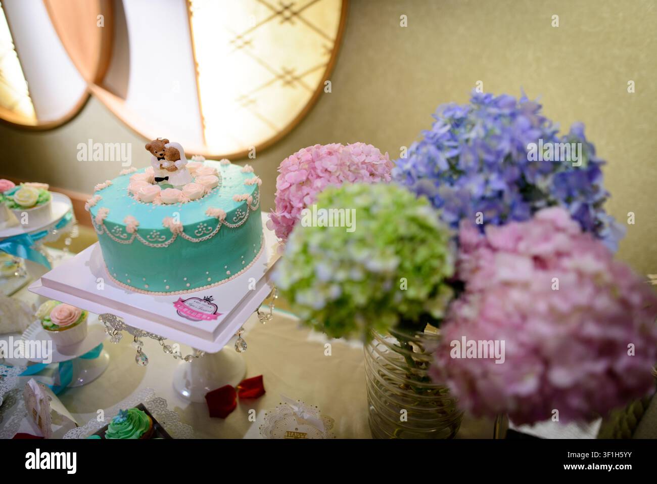 Un gâteau décoratif avec des décorations florales en exposition lors d'un événement. Banque D'Images