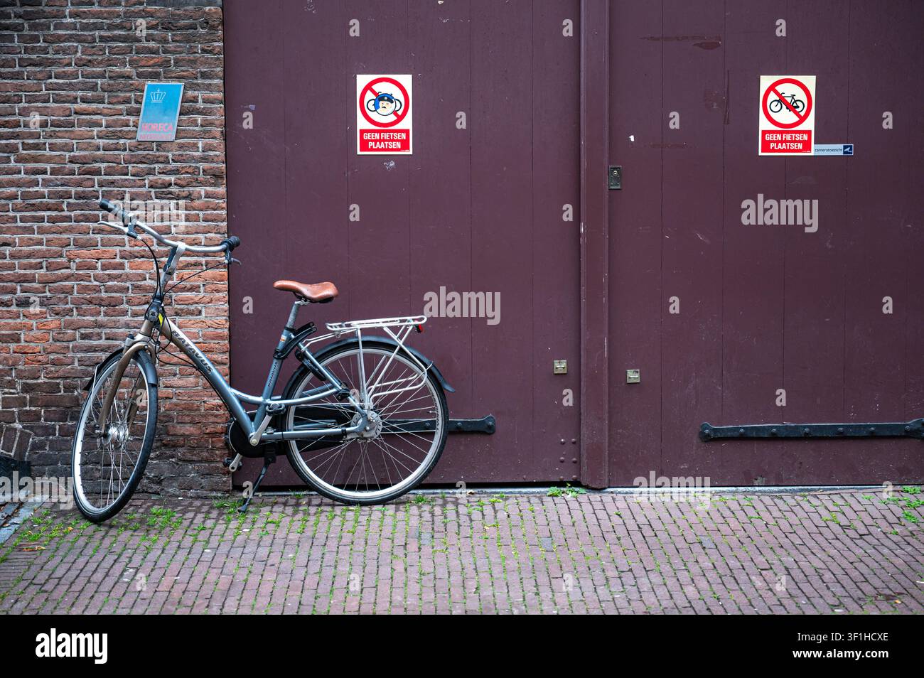 Un vélo garé contre une porte de garage affichant une pancarte interdisant le stationnement des vélos dans le centre historique de 's-Hertogenbosch. 's-Hertogenbosch, Net Banque D'Images