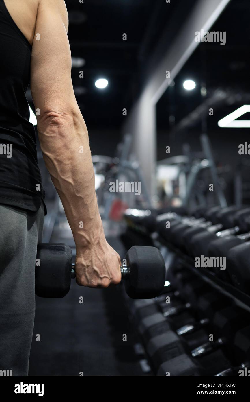 Homme musclé tenant une haltère lourde pendant un entraînement de force dans une salle de sport Banque D'Images