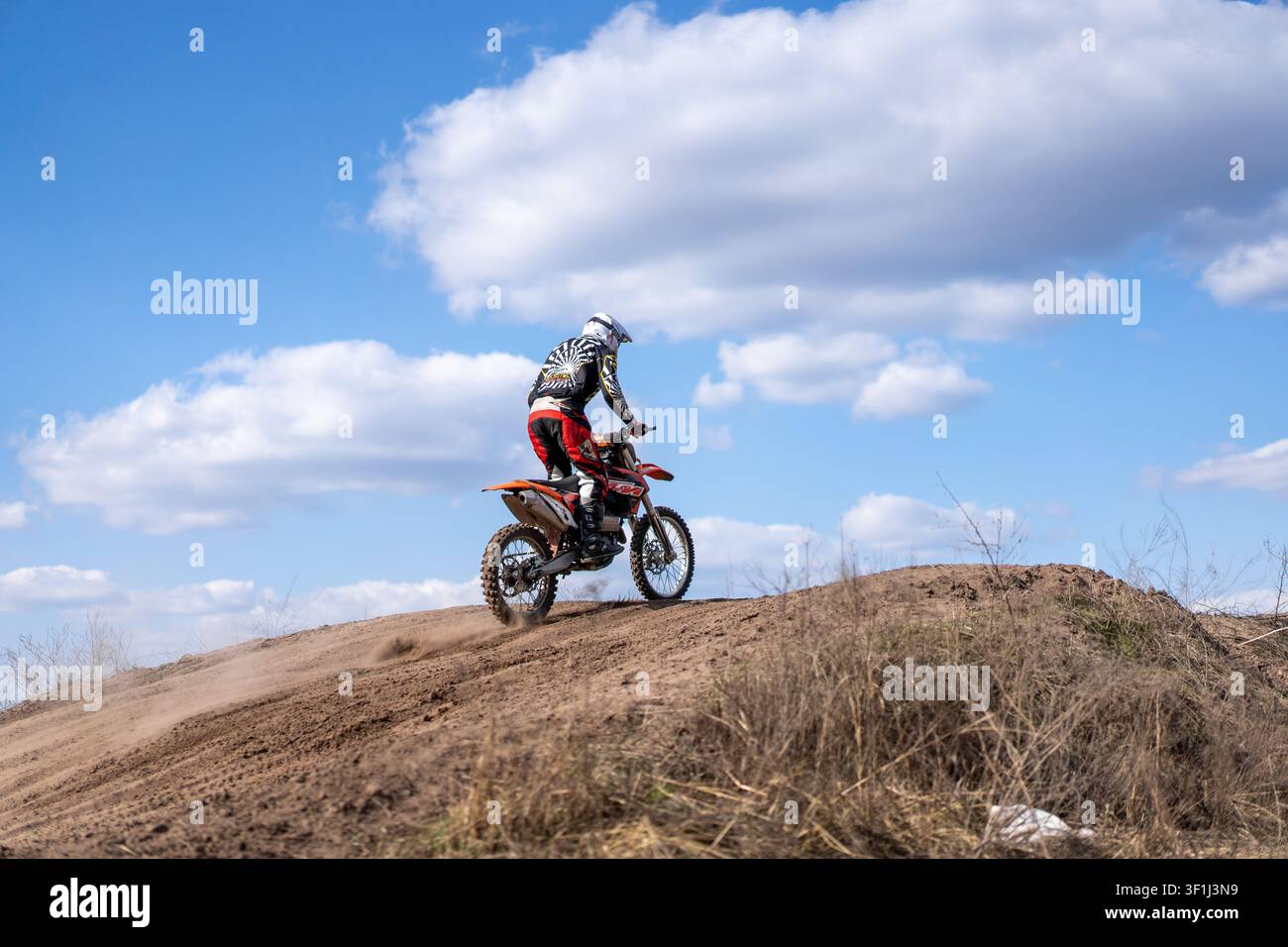 Kharkov Ukraine en mars 2021 Les motards s'entraînent sur une piste hors route. La scène montre une moto gravissant un monticule de terre tandis que des nuages remplissent le ciel bleu. Banque D'Images