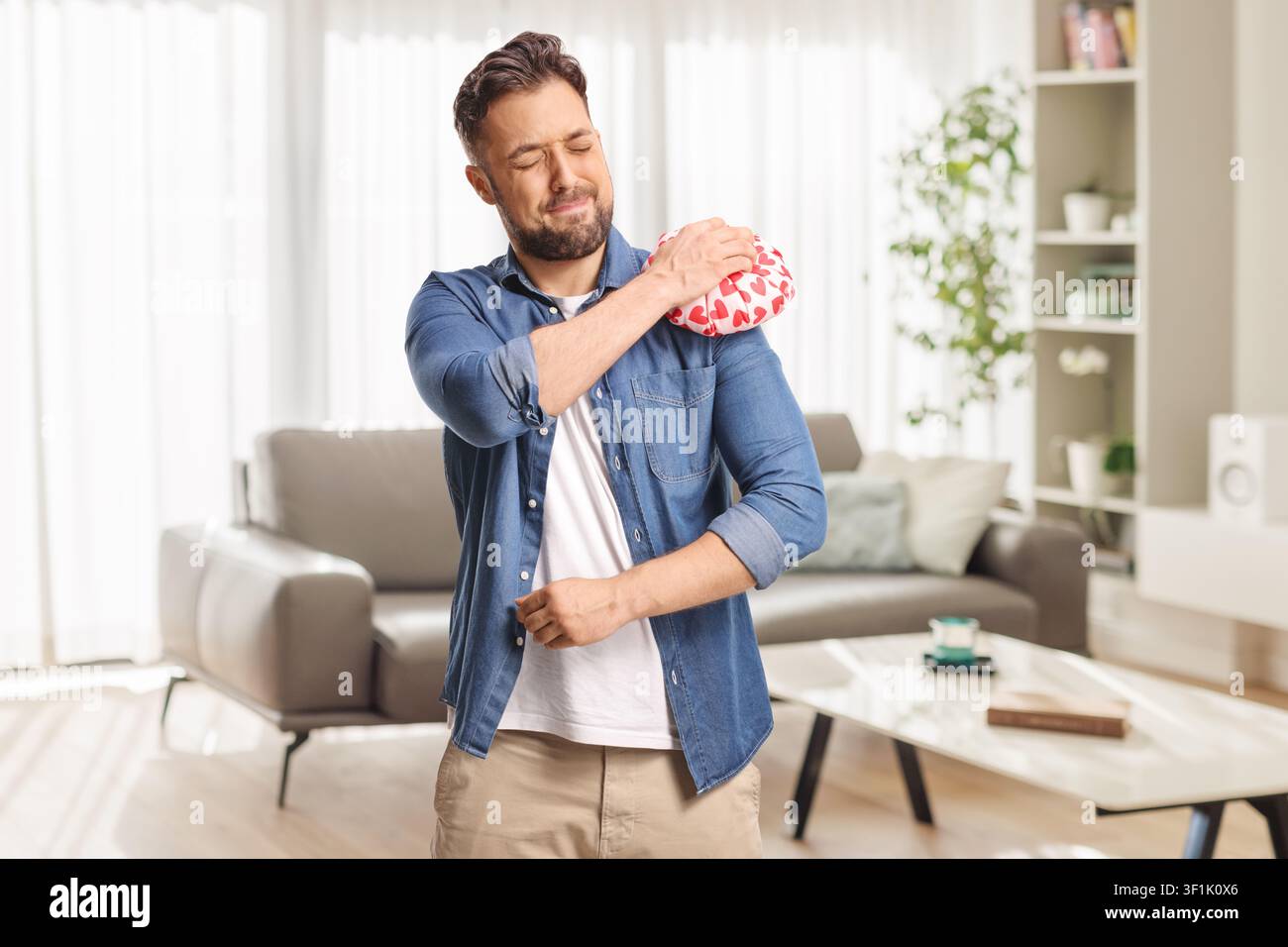 Homme souffrant d'une douleur à l'épaule utilisant une compresse de glace isolée sur fond blanc Banque D'Images