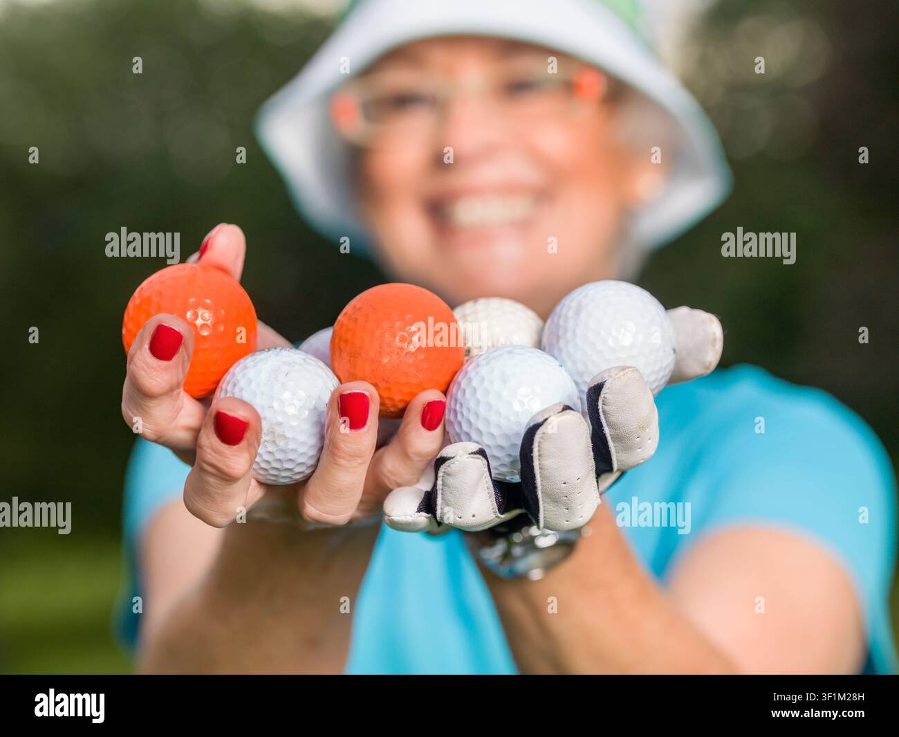 Portrait en gros plan d'une golfeuse âgée tenant plusieurs balles de golf dans ses mains Banque D'Images