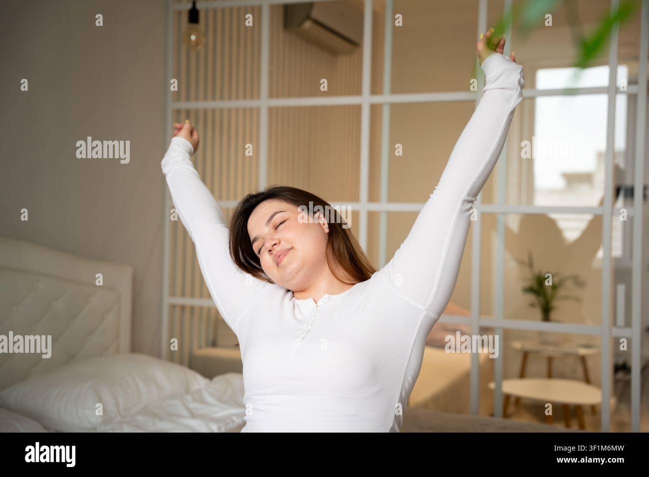 Femme s'étirant dans le lit pendant sa routine matinale dans une chambre confortable. Bien-être du sommeil, relaxation et commencer la journée avec énergie. Banque D'Images