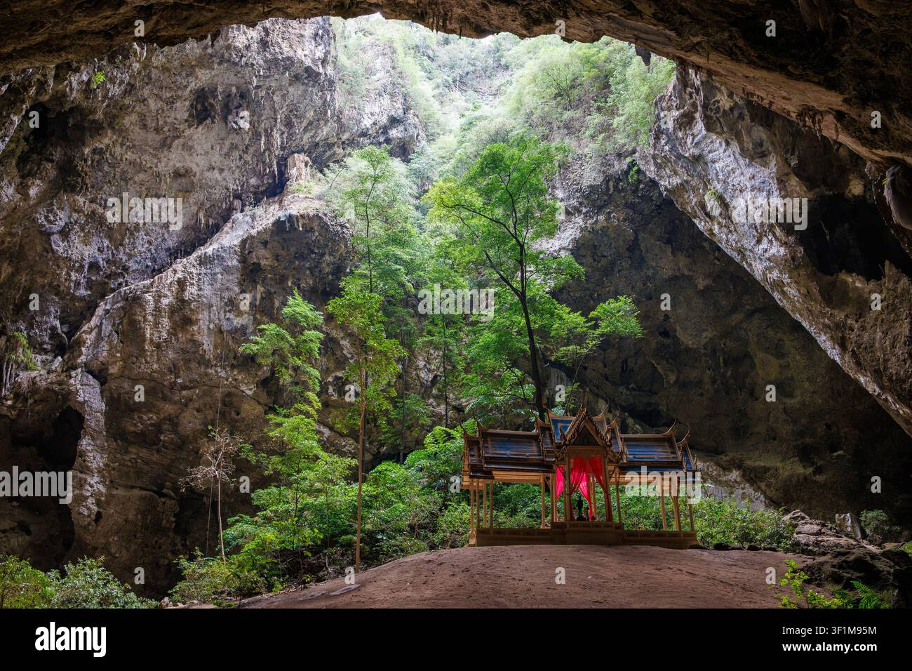 Le soleil filtre à travers une ouverture du toit dans une grotte et brille sur les arbres et le pavillon royal à l'intérieur de la grotte de Phraya Nakhon, Thaïlande Banque D'Images