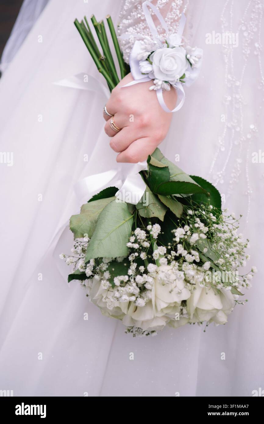 Close-up d'une mariée tenant un délicat bouquet de mariage blanc composé de roses fraîches et de gypsophile. La mariée porte une robe blanche Banque D'Images