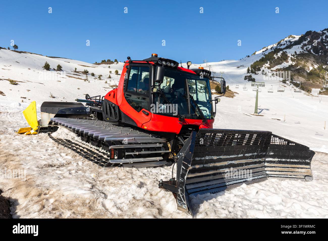 Une puissante machine de préparation de neige dans un paysage enneigé des Pyrénées par une journée d'hiver claire, préparant les pistes de ski pour les amateurs de plein air et l'hiver Banque D'Images