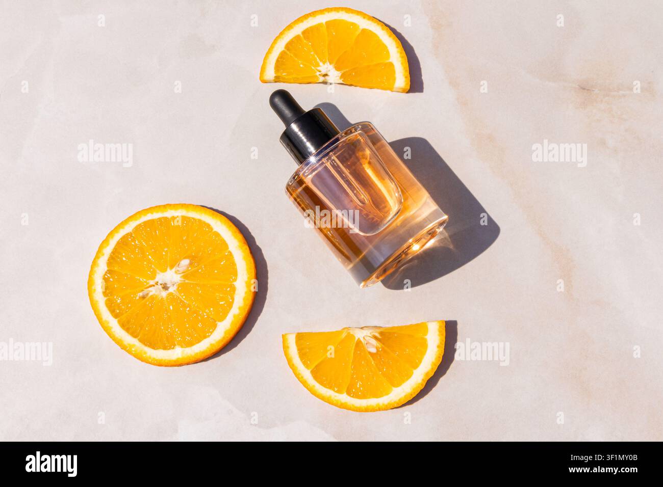Flacon de sérum de soins à la vitamine C avec compte-gouttes stylisé avec des tranches d'orange fraîches sur un fond beige, mettant en valeur le concept de produits cosmétiques aux agrumes, n Banque D'Images